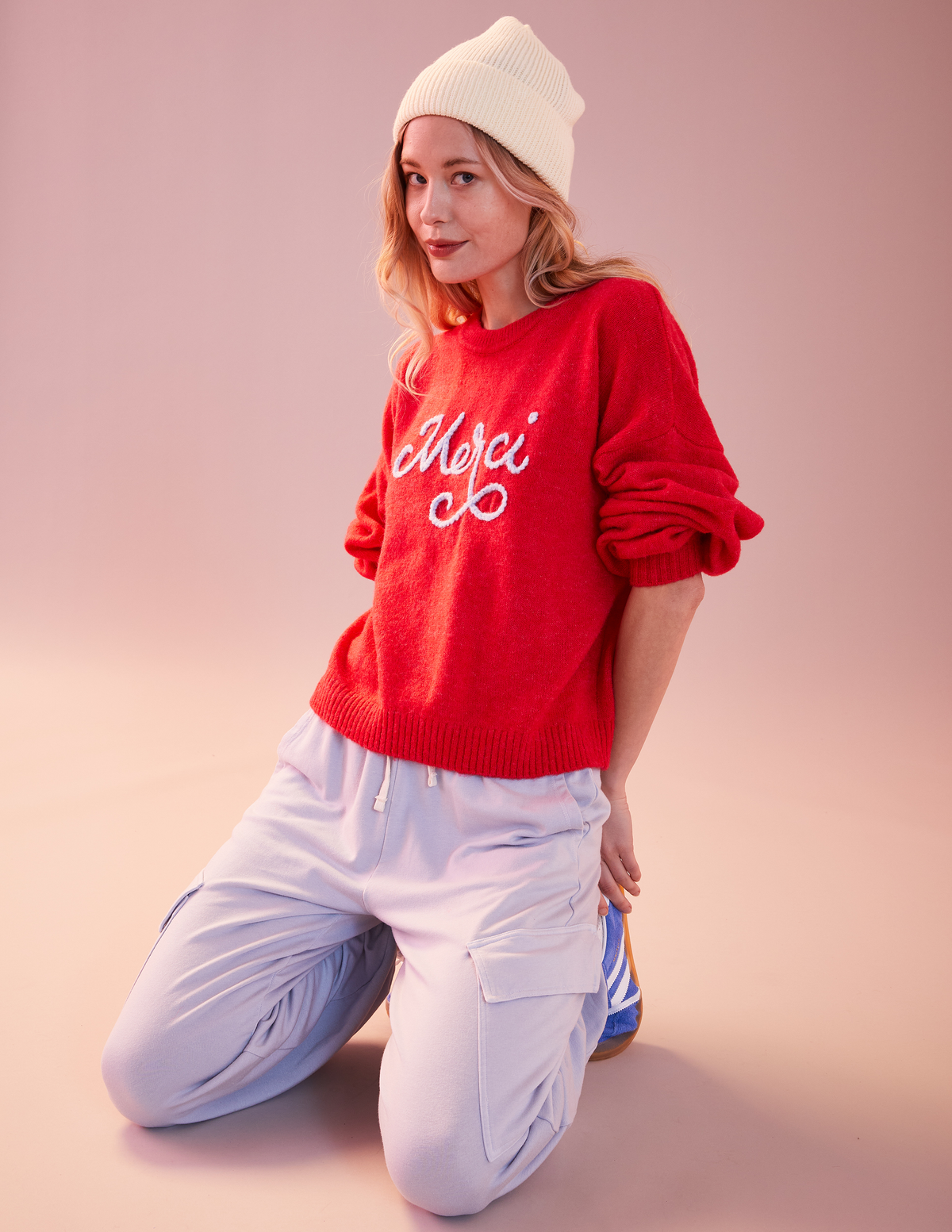 Sundry Merci Crew Neck Sweater-model is wearing a white beanies and a sweater with joggers and is kneeling down