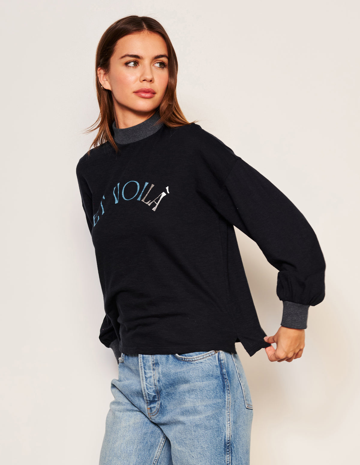 Sundry Et Voila Mock Neck Long Sleeve Tee in Deep Navy-model is looking to the side and holding her shirt behind her