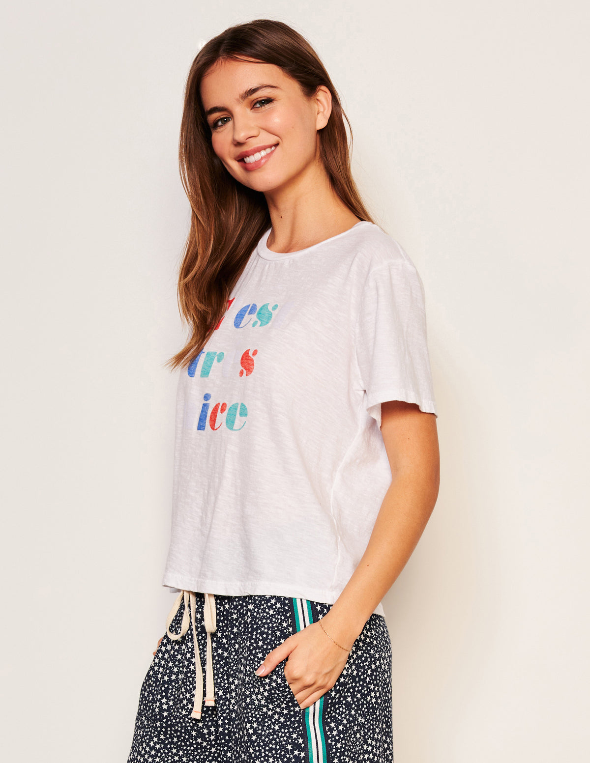Sundry C&#39;est Crew Neck Tee in Optic White-side view model is smiling and has her hand in her pocket