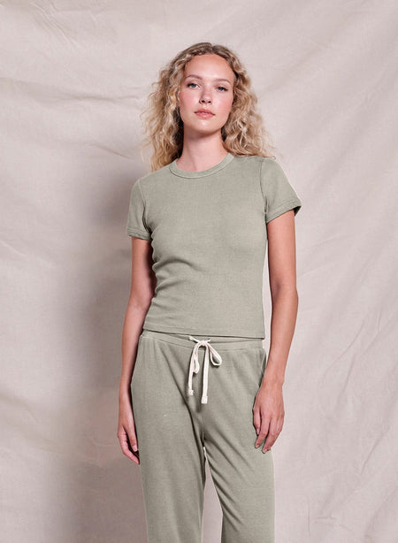 Woman wearing a green t-shirt and matching pants against a plain background