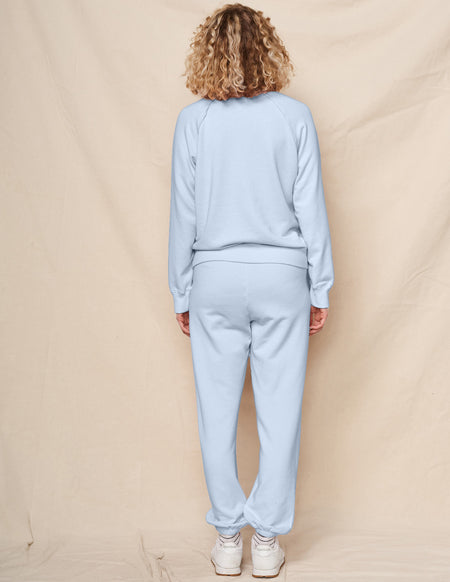 Woman wearing a light blue tracksuit against a beige background
