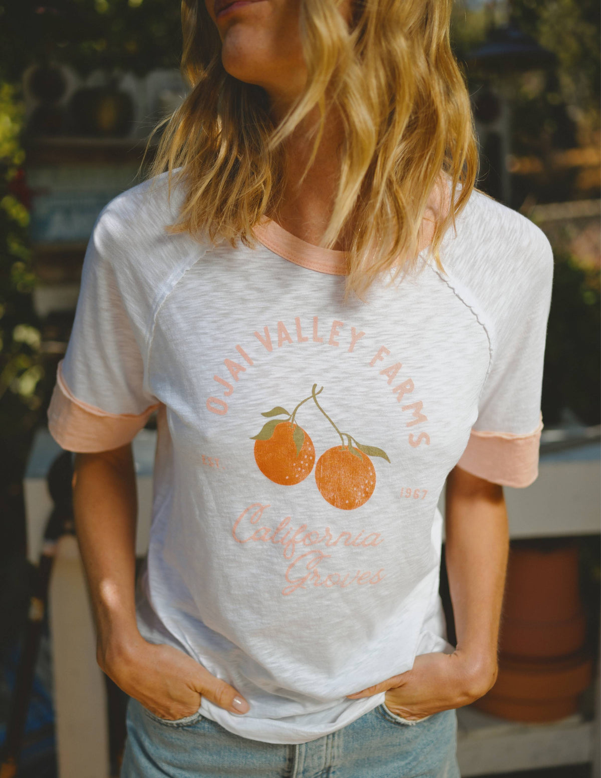 Person wearing a white t-shirt with a graphic design outdoors.