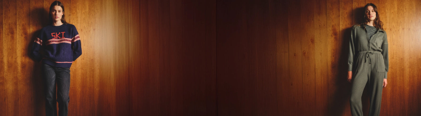 Two people wearing different outfits against a wooden wall.