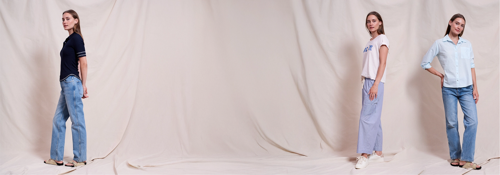 Three women modeling casual outfits in front of a soft beige fabric backdrop—one in a navy polo and jeans, one in a white tee and striped pants, and one in a light blue button-up and jeans